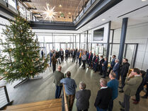 Zahlreiche Personen verfolgen die Übergabe eines Weihnachtsbaums im Neubau des Landtags.