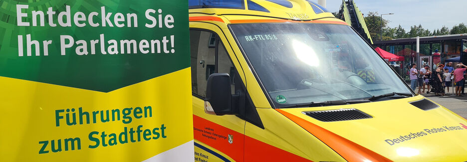 Werbeaufsteller für Führungen zum Stadtfest auf dem Vorplatz, im Hintegrund sind ein Rettungswagen sowie das Polizeimaskottchen Poldi zu erkennen.