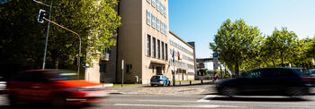 Vor dem Eingang des Landtag-Altbaus fahren ein rotes und ein schwarzes Auto vorbei.