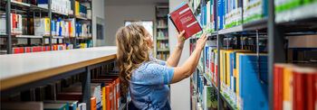 In der Bibliothek des Landtags stellt eine Frau Bücher in ein Regal.