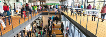 Im Bürgerfoyer laufen viele Leute im Erdgeschoss, auf der Treppe und im offenen Obergeschoss.