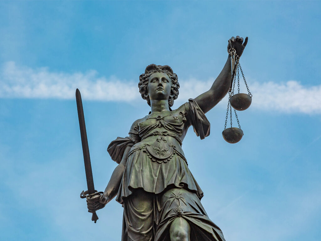 Statue der Justitia vor blauem Himmel.