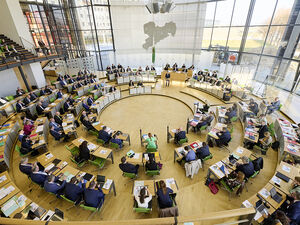 Blick von oben in den Plenarsaal, wo zahlreiche Abgeordnete während einer Plenarsitzung Platz genommen haben.