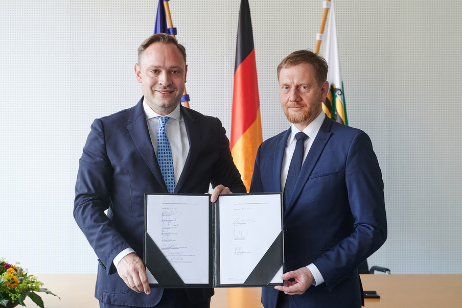Landtagspräsident Alexander Dierks und Ministerpräsident Michael Kretschmer präsentieren die unterzeichnete Eilausfertigung des Haushaltsgesetztes.