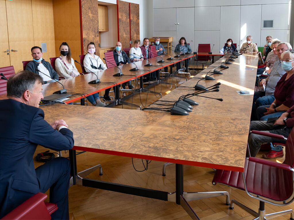 Zum Tag der offenen Tür sitzen Besucher mit dem Landtagspräsidenten im Sitzungssaal des Präsidiums.