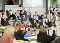 Abgeordnete im Plenarsaal mit gehobenen Händen während einer Abstimmung.