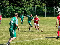 Fußballer in grünen und roten Trikots beim Fußballspielen auf dem Platz.