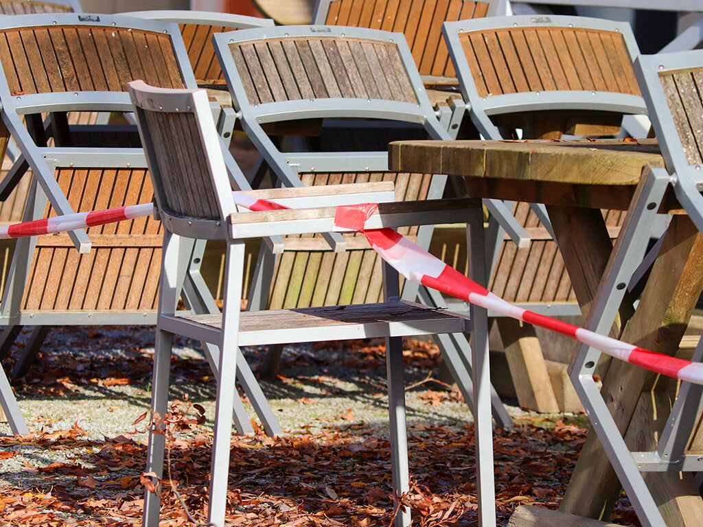 Leere Stühle, die mit einem Absperrband fixiert sind.