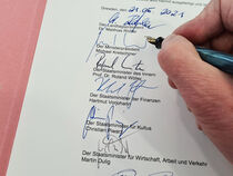 Hand mit Stift bei der Ausfertigung eines Gesetzes