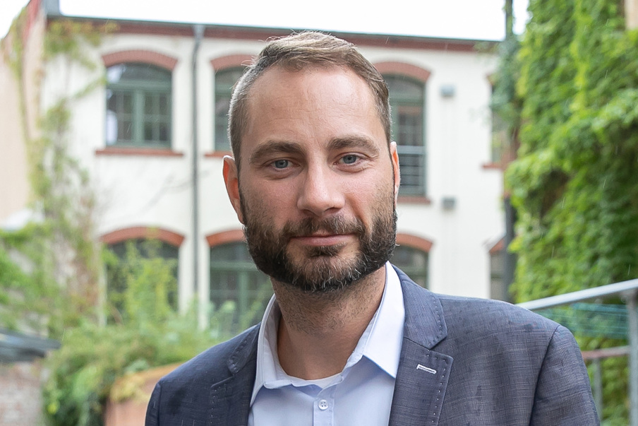 Porträt Patrick Schreiber vor einem Wohnhaus