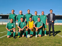 Die Mannschaft des FC Landtag steht in Sportkleidung für ein Gruppenfoto mit Landtagspräsident Dr. Rößler auf einem Spielfeld.