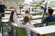 Jugendliche sitzen während einer Führung auf den Plätzen der Abgeordneten im Plenarsaal.