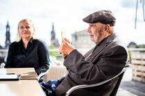 Prof. Peter Kulka und Katrin Leers-Kulka sitzen auf der Dachterrasse des Landtags. Im Hintergrund ist die Altstadtsilhouette von Dresden zu erahnen.