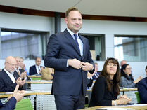 Alexander Dierks erhebt sich nach seiner Wahl vom Platz im Plenarsaal und ihm wird applaudiert.