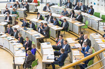 Abgeordnete sitzen im Plenarsaal während einer Plenarsitzung und verfolgen die Debatte.