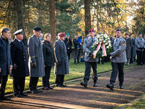 Kranzniederlegung auf dem Nordfriedhof Dresden, Bundeswehrangehörige tragen einen Kranz, an den Seiten stehen Menschen.