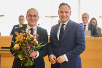 Landtagspräsident Alexander Dierks übergibt Martin Modschiedler Blumen nach seiner Wahl zum Integrationsbeauftragten.