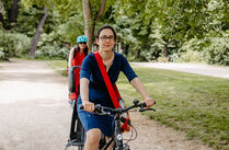 Claudia Maicher mit dem Fahrrad unterwegs in einem Leipziger Park, dahinter Redakteurin katja Ciesluk auf dem Rad