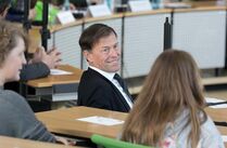 Der Landtagspräsident unterhält sich mit zwei jungen Rednern in den Sitzreihen des Plenarsaals 