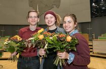 Die drei besten Redner des diesjährigen Jugend-Redeforums lächeln mit ihren Urkunden und Blumensträußen in die Kamera 