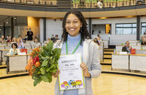 Aike Aúdú freut sich über ihre Urkunde und den Blumenstrauß für den 3. Platz