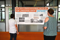 Besucherin betrachten eine Schautafel der Ausstellung des Sächsischen Landtags.
