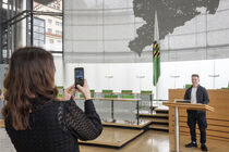Eine Frau macht mit dem Smartphone ein Foto eines Schülers, der am Rednerpult im Plenarsaal steht.