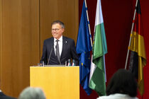 Landtagspräsident Dr. Matthias Rößler spricht am Rednerpult, hinter ihm sind Flaggen von Sachsen, Deutschland und Europa zu zu sehen.