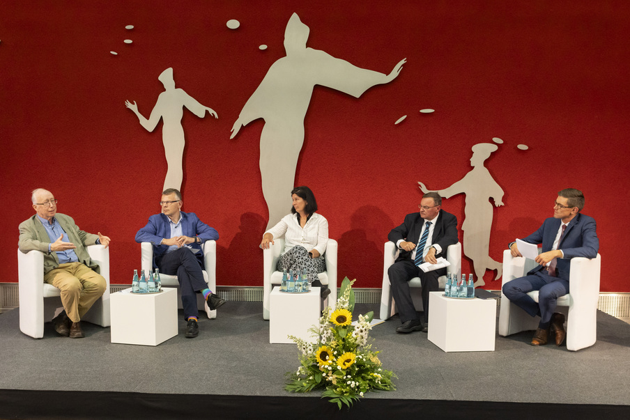 Die Teilnehmer der Podiumsdiskussion sitzen auf dem Podium und diskutieren.