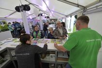 Besucher informieren sich an einem Stand im Zelt