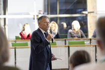 Landtagspräsident Dr. Matthias Rößler steht mit einem Mikrofon im Plenarsaal und begrüßt die Teilnehmer.