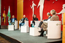 Die Teilnehmer der Podiumsdiskussion sitzen auf dem Podium und diskutieren.