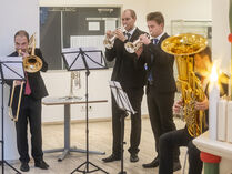 Blasmusiker spielen neben der Weihnachtspyramide Weihnachtslieder.