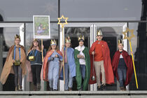 Sechs Sternsingerkinder mit Kostümen und Spendenboxen vor den Glastüren des Neubaus beim Gang aus dem Parlament.