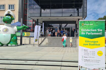 Eingang zum Landtag, flankiert von Polizeimaskottchen Poldi und einem Werbebanner für die Führungen zum Stadtfest.