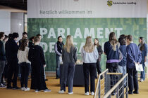 Besuchergruppe steht im Kreis um das Landtagsmodell.
