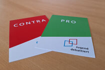 Auf einem Tisch liegen zwei Karten mit der Aufschrift Pro bzw. Contra.