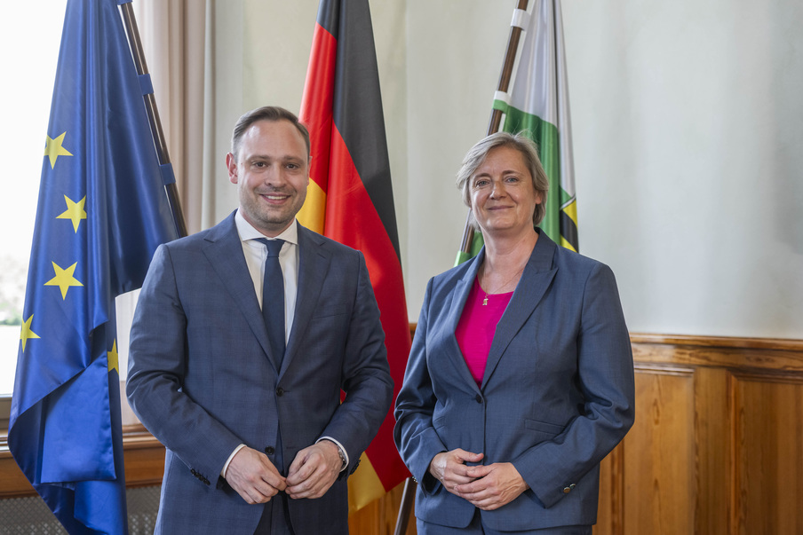 Landtagspräsident Alexander Dierks mit Alda Vanaga, Botschafterin der Republik Lettland vor drei Fahnen (Europa, Deutschland, Sachsen).
