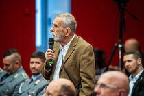 Gast im Publikum spricht in ein Mikrofon.