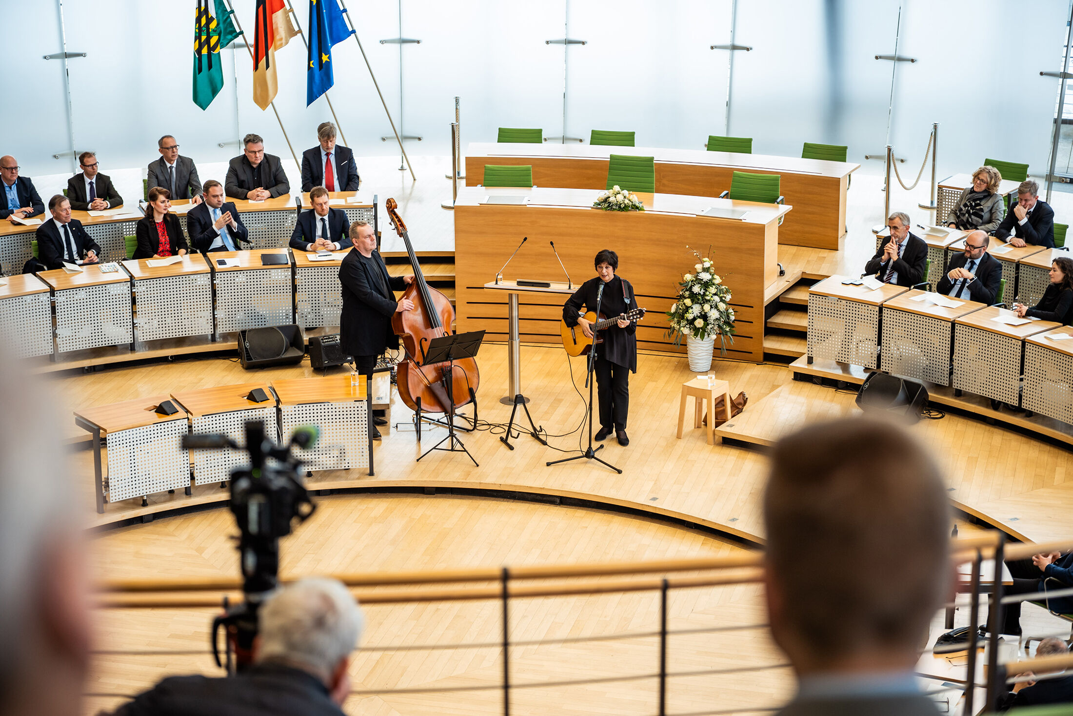 Bente Kahan singt im Plenarsaal des Sächsischen Landtags, im Hintergrund wichtige Politikerinnen und Politiker des Freistaats Sachsen
