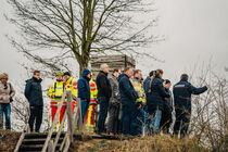 Die Ausschussdelegation steht auf einem Hügel, um Ausblick auf die Geräte der Feuerwehr zu haben.