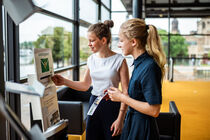 Beide Mädchen stehen vor dem Briefkasten im Bürgerfoyer und werfen eine Postkarte ein.