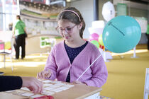 Ein Mädchen spielt Memory und hält einen Luftballon