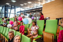Kleine sitzende Mädchen mit Luftballons