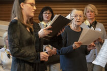 Mehrere Frauen halten Liederbücher in der Hand und singen.