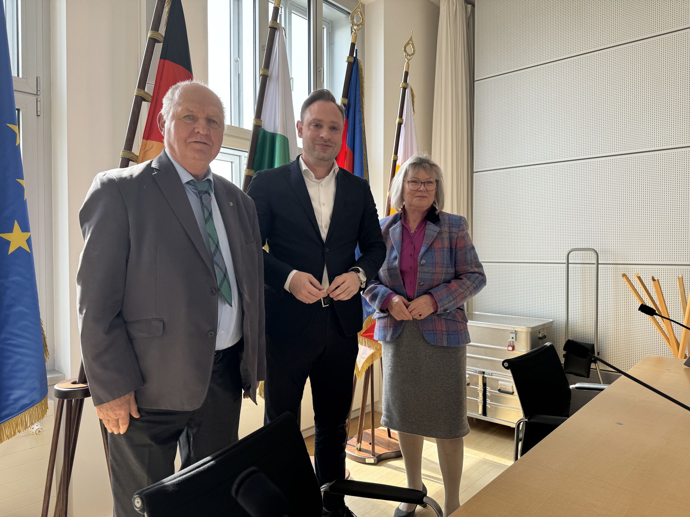 Landtagspräsident Alexander Dierks und zwei Mitglieder des VeMdL stehen in einem Sitzungssaal.